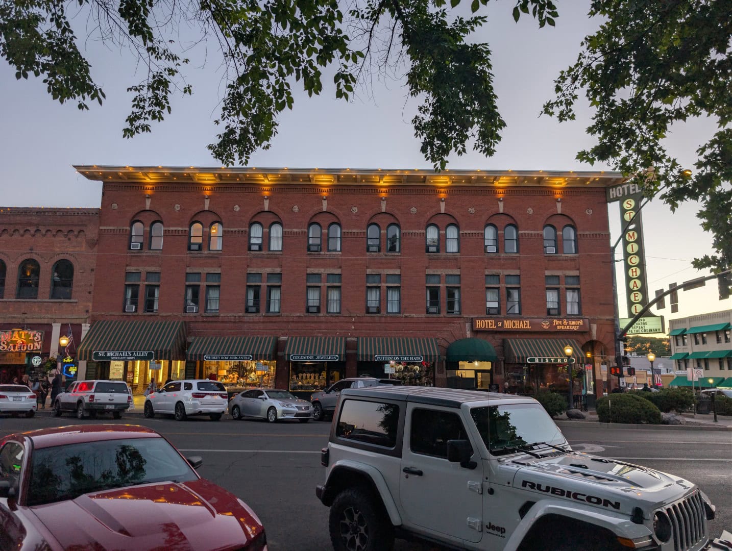 Hotel St. Michael at dusk with its lit roofline and vertical neon sign at the corner of Whiskey Row in Prescott, Arizona