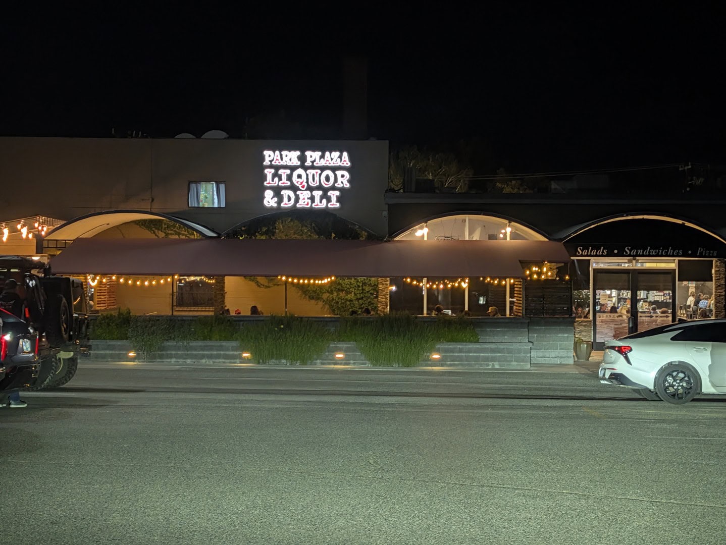 Park Plaza Liquor & Deli lit up at night with string lights over its covered patio on West Goodwin Street in Prescott, Arizona
