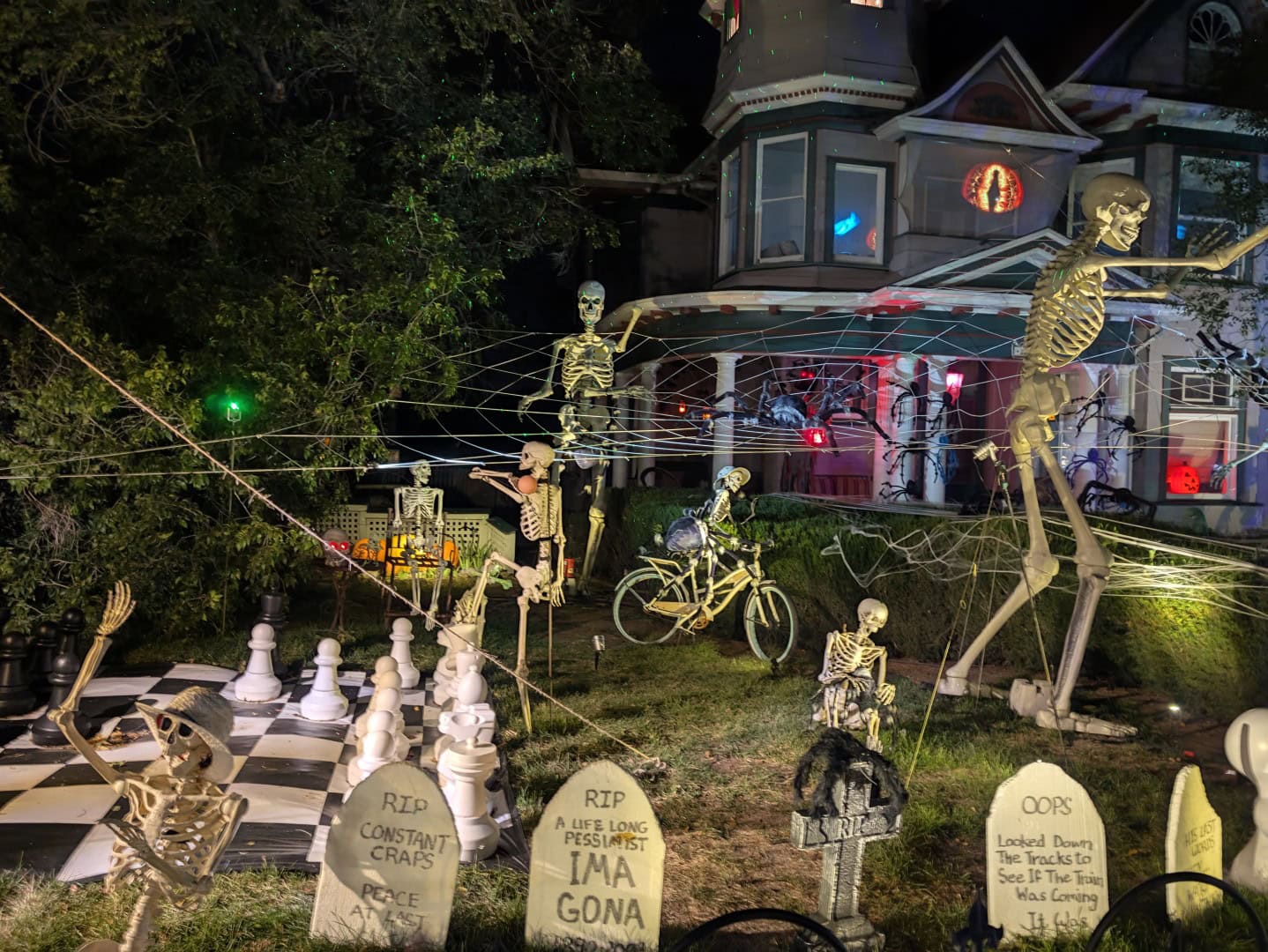 Victorian house decorated for Halloween with giant skeletons, spider webs, a skeleton on a bicycle, and joke tombstones in Prescott, Arizona