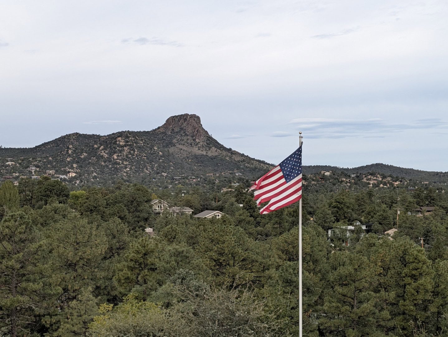 American flag waving over ponderosa pines with Thumb Butte on the skyline in Prescott, Arizona